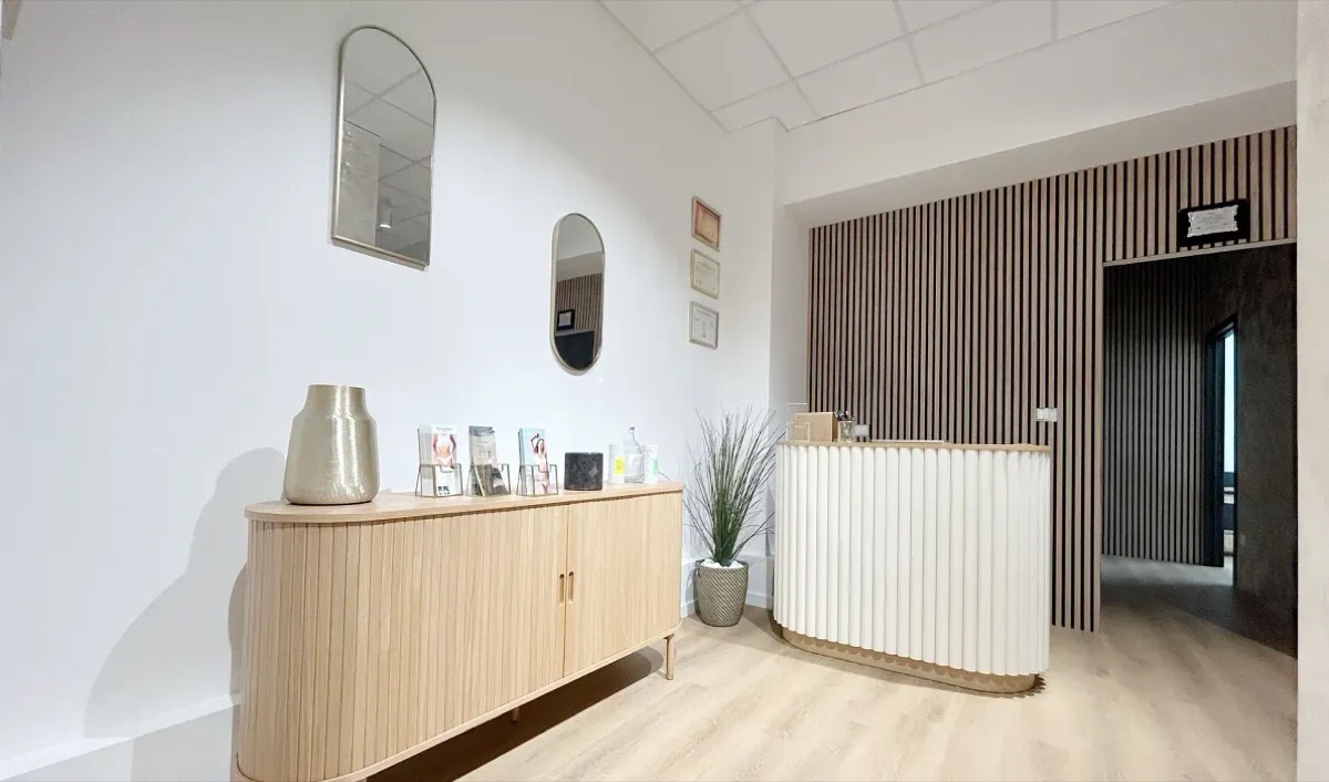 L'accueil du centre : meuble en bois clair, miroirs, comptoir blanc